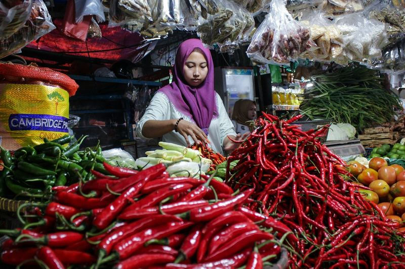 A market trader at her stall of fresh chillies and vegetables