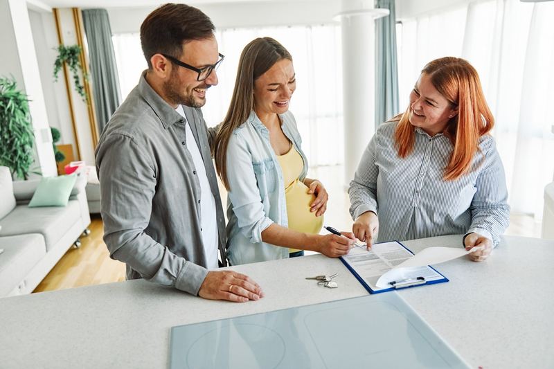 An adviser going through paperwork with two smiling clients at a table