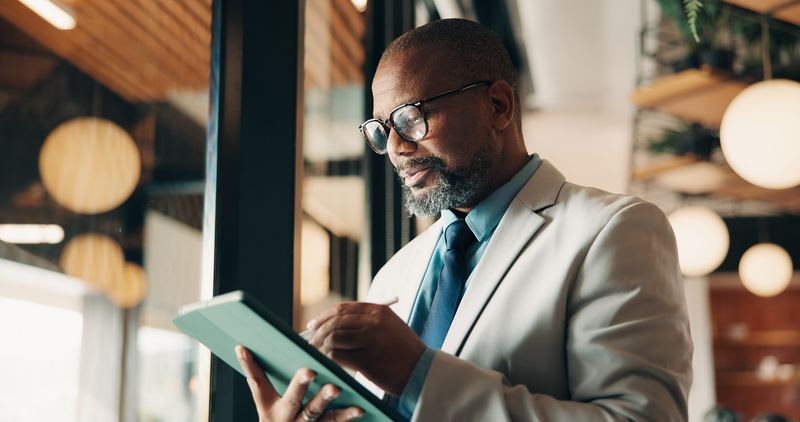 A business owner in a suit checking his tablet